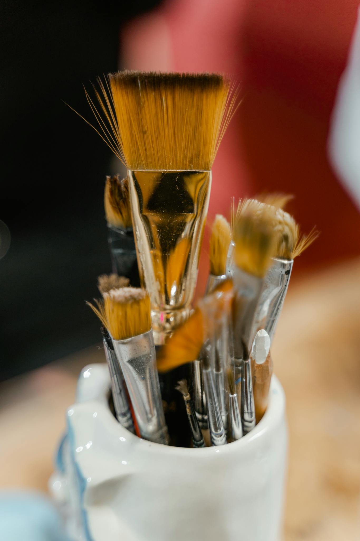 A variety of paintbrushes in a white ceramic holder, ideal for art and creativity themes.